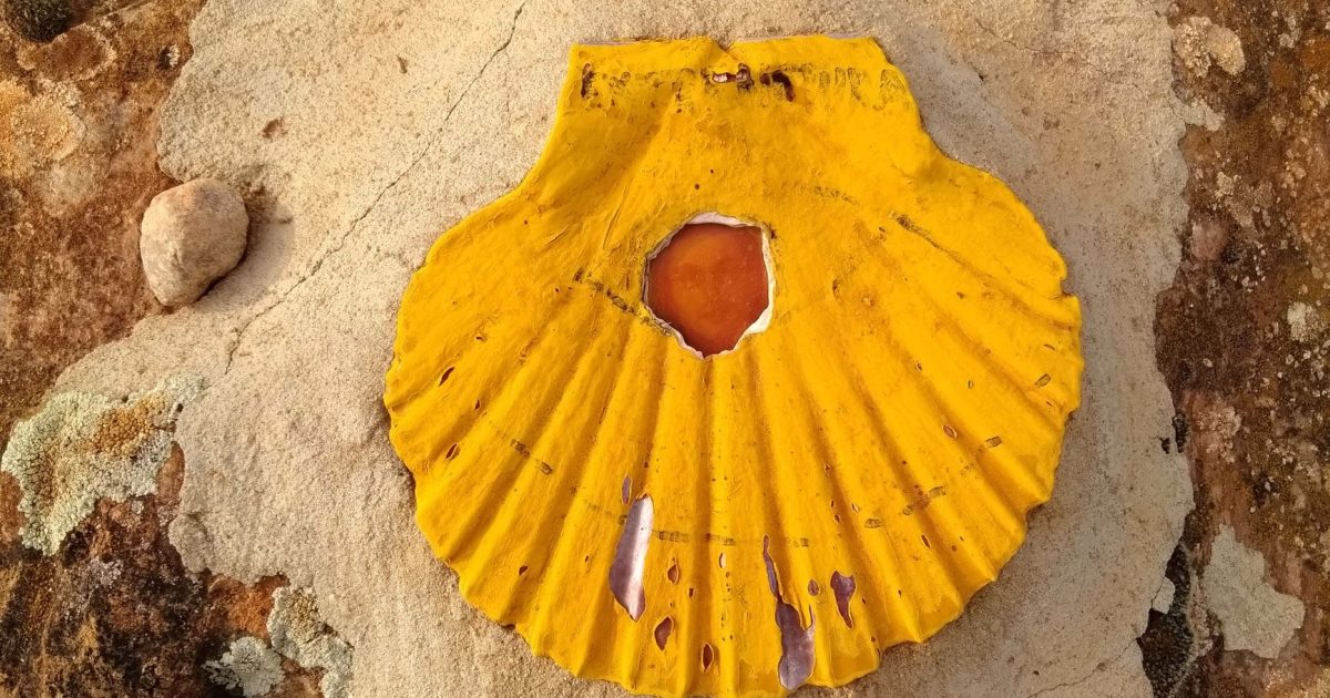 Concha de vieira amarilla pintada sobre una roca, uno de los símbolos que señalan el Camino de Santiago