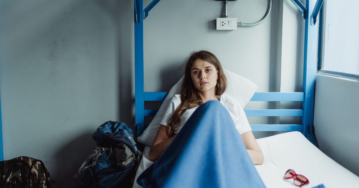 Joven tumbada en la litera de un albergue junto a su equipaje, el lugar donde se usa el saco de dormir del Camino