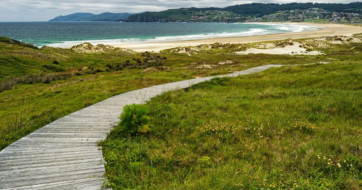peregrino caminando sendero costero con vistas al mar Galicia
