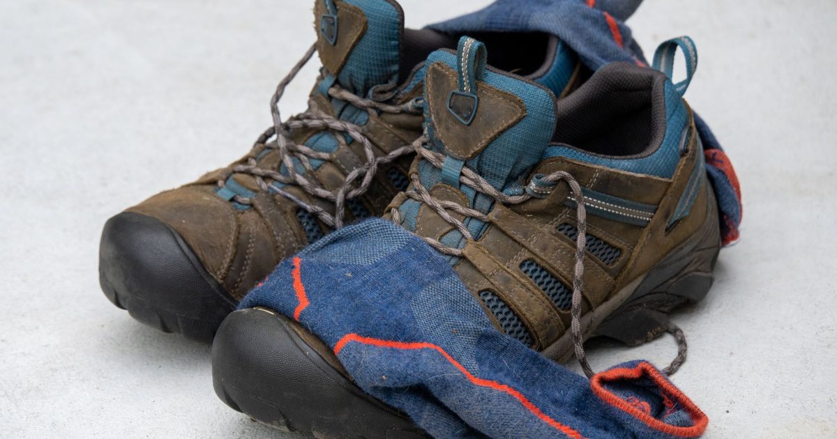 Zapatillas de senderismo junto a unos calcetines de lana gastados, el equipo básico para cuidar los pies en el Camino